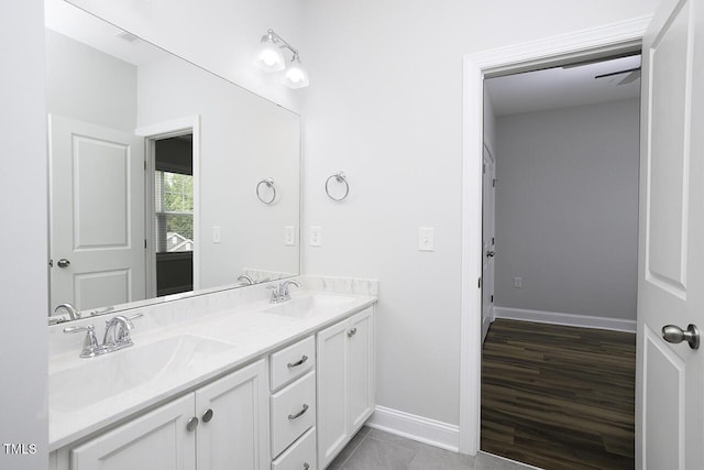 full bath featuring double vanity and baseboards