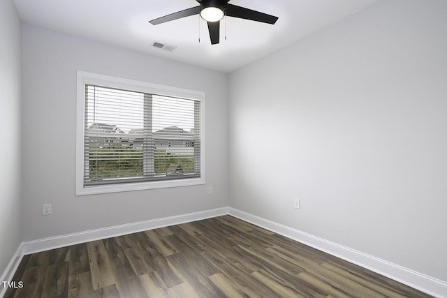 empty room featuring a ceiling fan, dark wood-style flooring, and baseboards