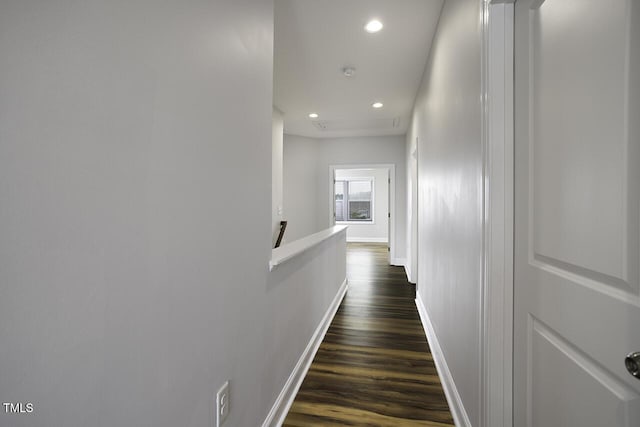 hall featuring an upstairs landing, dark wood-style flooring, baseboards, and recessed lighting