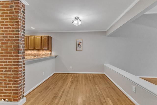 unfurnished dining area featuring light wood-type flooring, baseboards, and crown molding