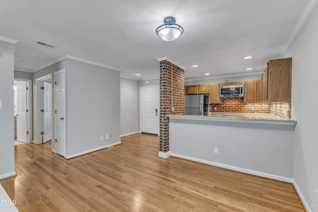 kitchen featuring appliances with stainless steel finishes, light wood-style flooring, decorative backsplash, baseboards, and ornamental molding