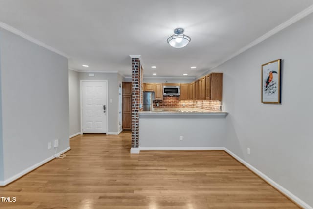 kitchen with stainless steel appliances, crown molding, tasteful backsplash, light wood-type flooring, and a peninsula