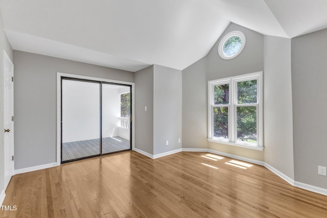 unfurnished bedroom featuring wood finished floors, baseboards, and high vaulted ceiling