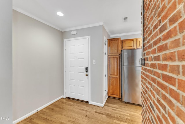 kitchen featuring freestanding refrigerator, light wood finished floors, crown molding, and baseboards