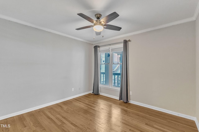 empty room with wood finished floors, crown molding, baseboards, and a ceiling fan
