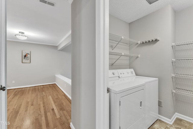 laundry room featuring washer and clothes dryer, light wood-style flooring, baseboards, and ornamental molding