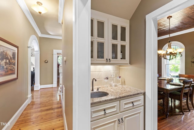 1329 Wynncrest Ct, Raleigh, NC 27603 - indoor wet bar with crown molding, light wood finished floors, a chandelier, decorative backsplash, and baseboards