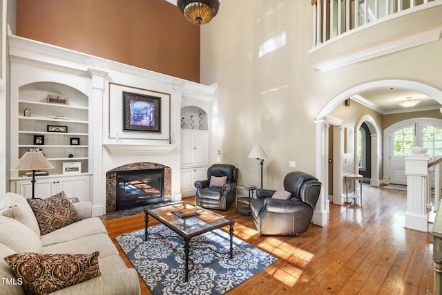 1329 Wynncrest Ct, Raleigh, NC 27603 - living room featuring arched walkways, built in features, hardwood / wood-style floors, a high ceiling, and a premium fireplace