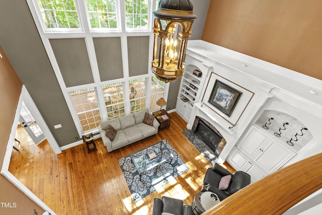 1329 Wynncrest Ct, Raleigh, NC 27603 - living room with a high ceiling, wood-type flooring, a glass covered fireplace, baseboards, and a chandelier