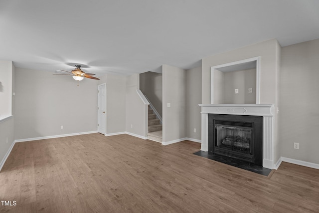 1313 Legacy Greene Ave, Wake Forest, NC 27587 - unfurnished living room featuring stairs, wood finished floors, a fireplace with flush hearth, and a ceiling fan