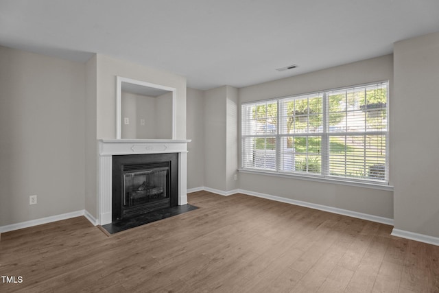 1313 Legacy Greene Ave, Wake Forest, NC 27587 - unfurnished living room featuring a fireplace with flush hearth, baseboards, wood finished floors, and healthy amount of natural light