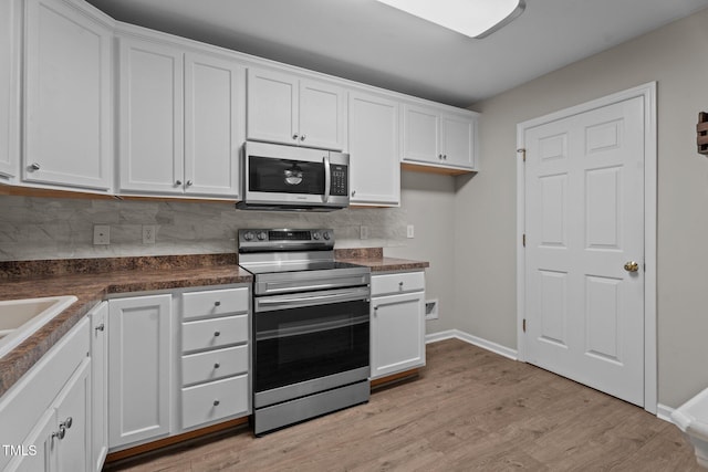 1313 Legacy Greene Ave, Wake Forest, NC 27587 - kitchen featuring stainless steel appliances, white cabinetry, dark countertops, backsplash, and light wood-style floors
