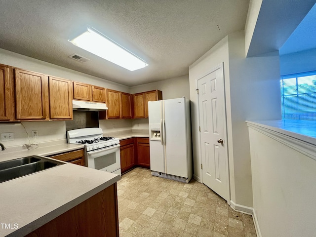 5911 Endsley Ct, Raleigh, NC 27610 - kitchen with white appliances, under cabinet range hood, a sink, brown cabinetry, and light countertops