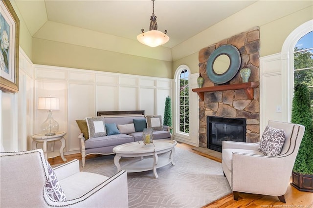  - living room with a decorative wall, a stone fireplace, and wood finished floors