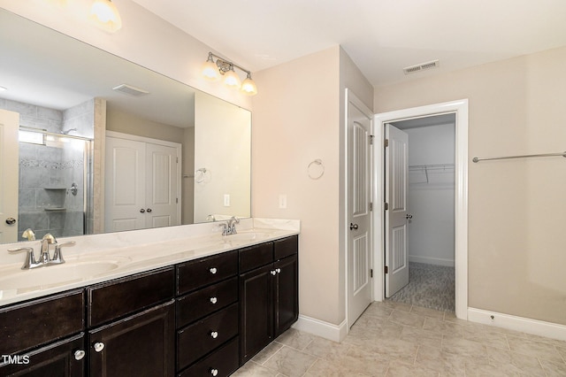 123 Gunderson Ln, Garner, NC 27529 - bathroom with double vanity, a shower stall, baseboards, a walk in closet, and tile patterned flooring