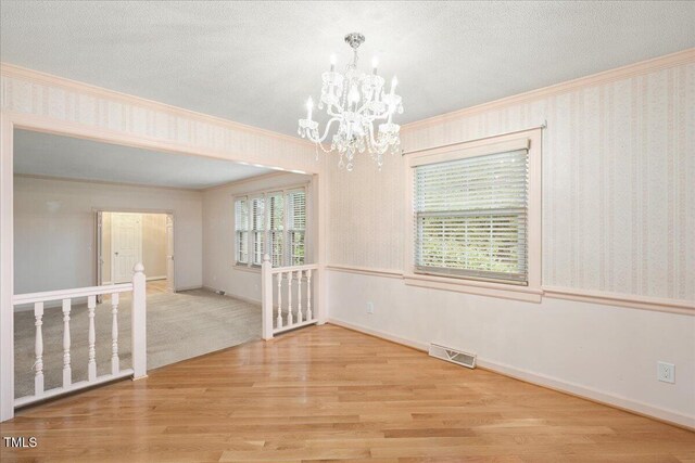 8133 Holly Forest Rd, Wake Forest, NC 27587 - unfurnished room with crown molding, a chandelier, wood finished floors, baseboards, and a textured ceiling