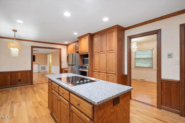 8133 Holly Forest Rd, Wake Forest, NC 27587 - kitchen featuring appliances with stainless steel finishes, a wainscoted wall, brown cabinetry, light wood-style floors, and a center island