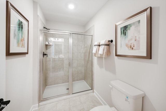 bathroom featuring toilet, baseboards, and a shower stall