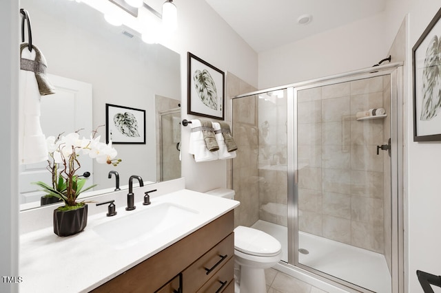 bathroom featuring a shower stall, toilet, vanity, and tile patterned flooring