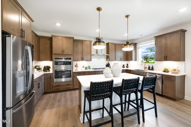 kitchen featuring stainless steel appliances, decorative backsplash, a kitchen bar, light countertops, and light wood-type flooring