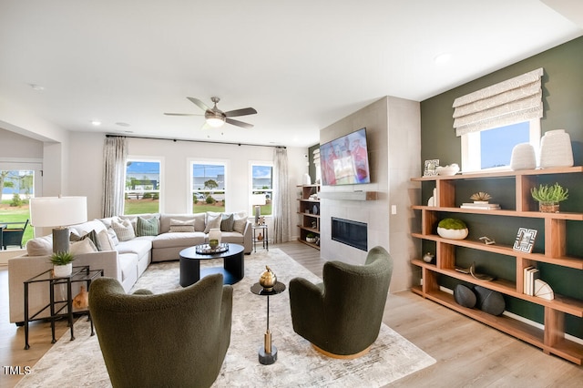 living area with wood finished floors, a tiled fireplace, ceiling fan, and recessed lighting