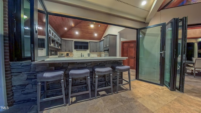 3197 Carriage Creek Ct, Haw River, NC 27258 - kitchen featuring a kitchen bar, gray cabinets, lofted ceiling, a peninsula, and tasteful backsplash