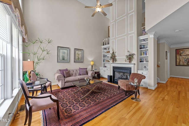 3923 Napa Valley Dr, Raleigh, NC 27612 - living room with a glass covered fireplace, a ceiling fan, a high ceiling, wood finished floors, and baseboards