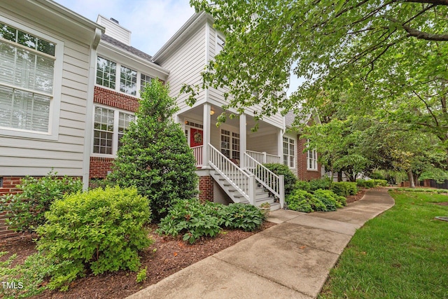 3923 Napa Valley Dr, Raleigh, NC 27612 - view of front of property featuring covered porch, a chimney, brick siding, stairway, and a front yard