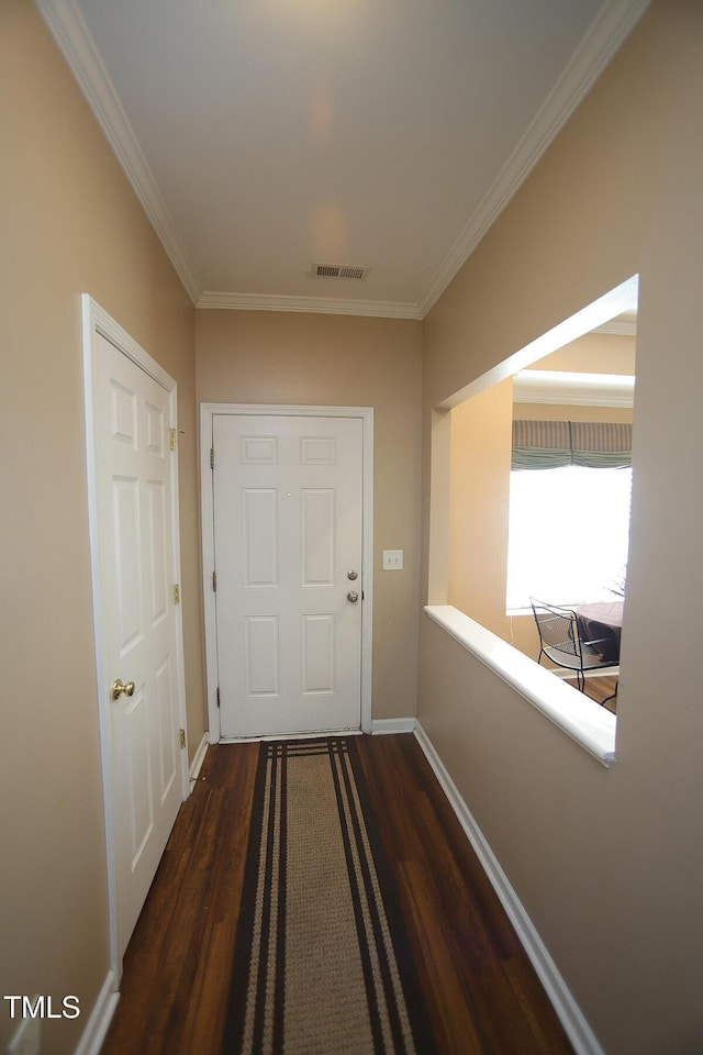 doorway with dark wood-type flooring, crown molding, and baseboards