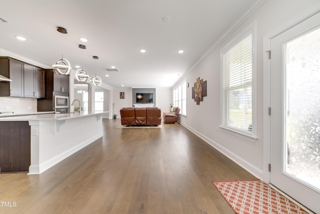 5420 Mill Dam Rd, Wake Forest, NC 27587 - kitchen with light countertops, ornamental molding, stainless steel microwave, open floor plan, and dark brown cabinets