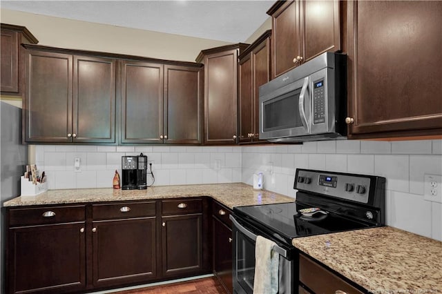 213 Windwood Dr, Stedman, NC 28391 - kitchen featuring appliances with stainless steel finishes, dark brown cabinetry, tasteful backsplash, and light stone countertops
