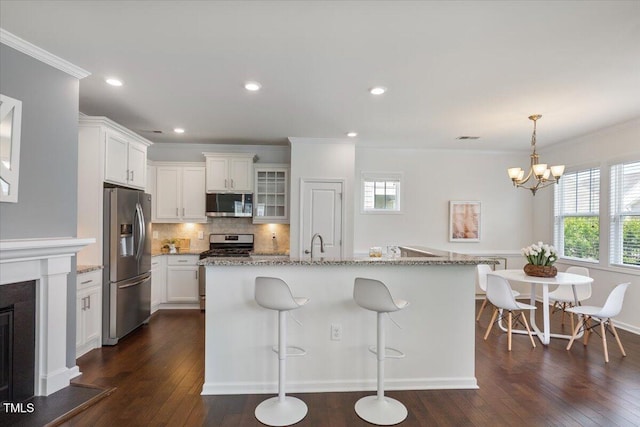 2837 Milano Ave, Apex, NC 27502 - kitchen featuring appliances with stainless steel finishes, dark wood-type flooring, healthy amount of natural light, white cabinetry, and crown molding