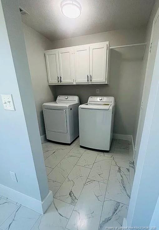 7690 Beverly Dr, Fayetteville, NC 28314 - washroom with baseboards, cabinet space, light marble finish flooring, washing machine and dryer, and a textured ceiling