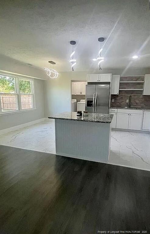 7690 Beverly Dr, Fayetteville, NC 28314 - kitchen featuring stainless steel fridge, separate washer and dryer, a textured ceiling, white cabinets, and a center island
