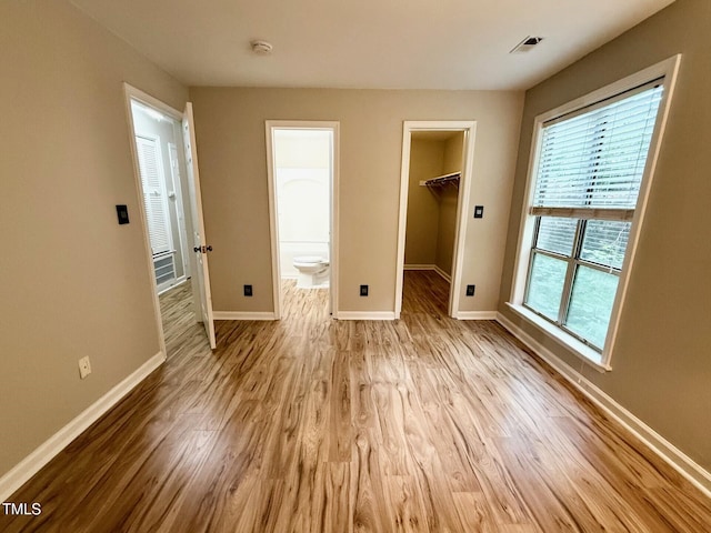 4120 Sedgewood Dr Unit 106, Raleigh, NC 27612 - unfurnished bedroom featuring baseboards, wood finished floors, a walk in closet, a closet, and ensuite bath