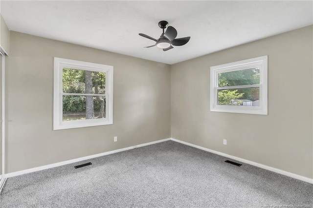 carpeted spare room featuring healthy amount of natural light, baseboards, and a ceiling fan