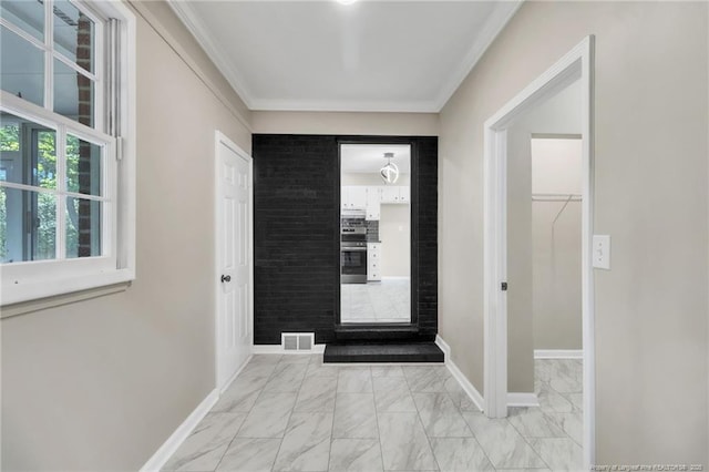 hallway with light marble finish floors, crown molding, and baseboards