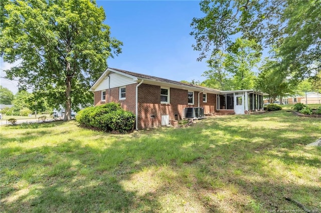 back of house with a sunroom, brick siding, a yard, and central air condition unit