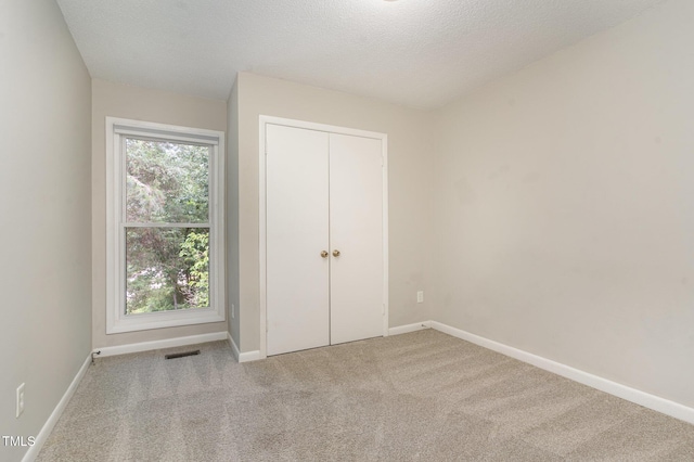 1304 Seaton Rd Unit 1, Durham, NC 27713 - unfurnished bedroom featuring carpet floors, baseboards, a textured ceiling, and a closet