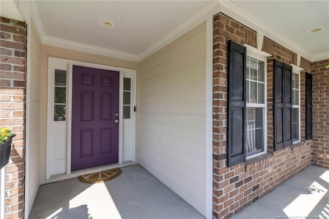 view of exterior entry with brick siding and covered porch