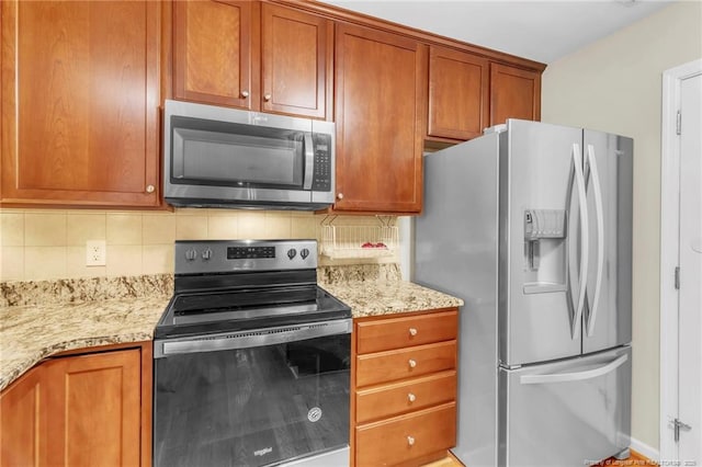 kitchen featuring appliances with stainless steel finishes, tasteful backsplash, light stone countertops, and brown cabinets