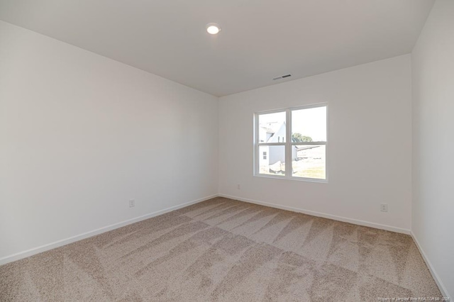 empty room featuring light colored carpet, baseboards, and recessed lighting