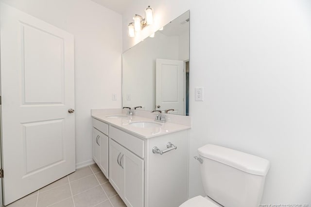 bathroom with toilet, tile patterned flooring, double vanity, and baseboards