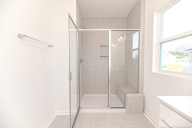 bathroom featuring tile patterned flooring, a shower stall, baseboards, and vanity