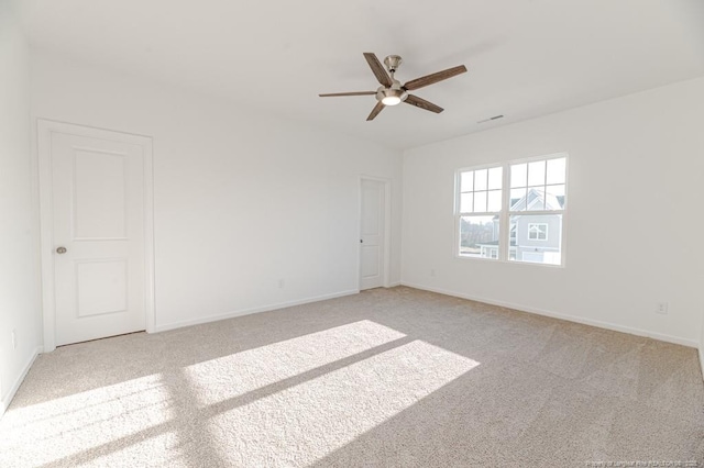 unfurnished room featuring light colored carpet, a ceiling fan, and baseboards