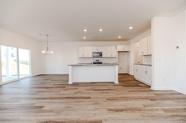 kitchen with stainless steel microwave, recessed lighting, light wood finished floors, a chandelier, and white cabinets