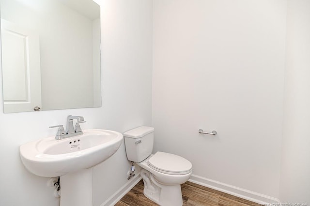 bathroom with wood finished floors, toilet, baseboards, and a sink