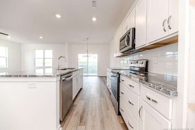 kitchen featuring stainless steel appliances, a sink, an island with sink, plenty of natural light, and recessed lighting