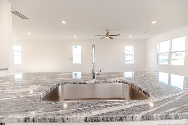 kitchen view of a sink, stone counters, recessed lighting, and ceiling fan