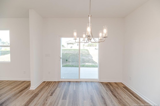 unfurnished dining area featuring a chandelier, wood finished floors, and baseboards